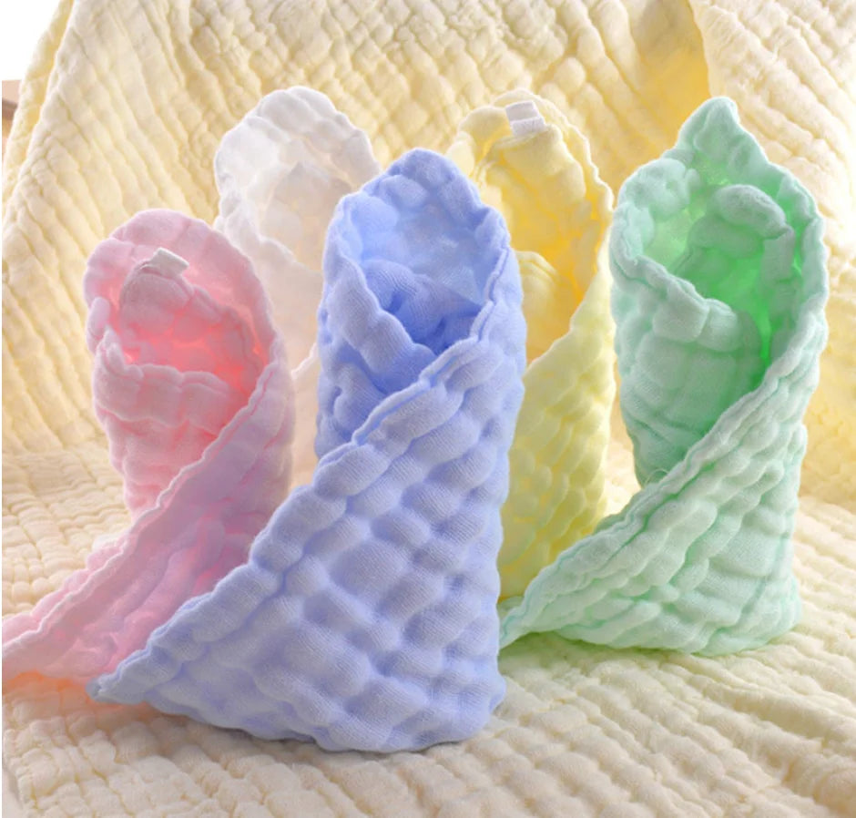 Three colorful baby blankets in pink, blue, and green on a textured yellow background