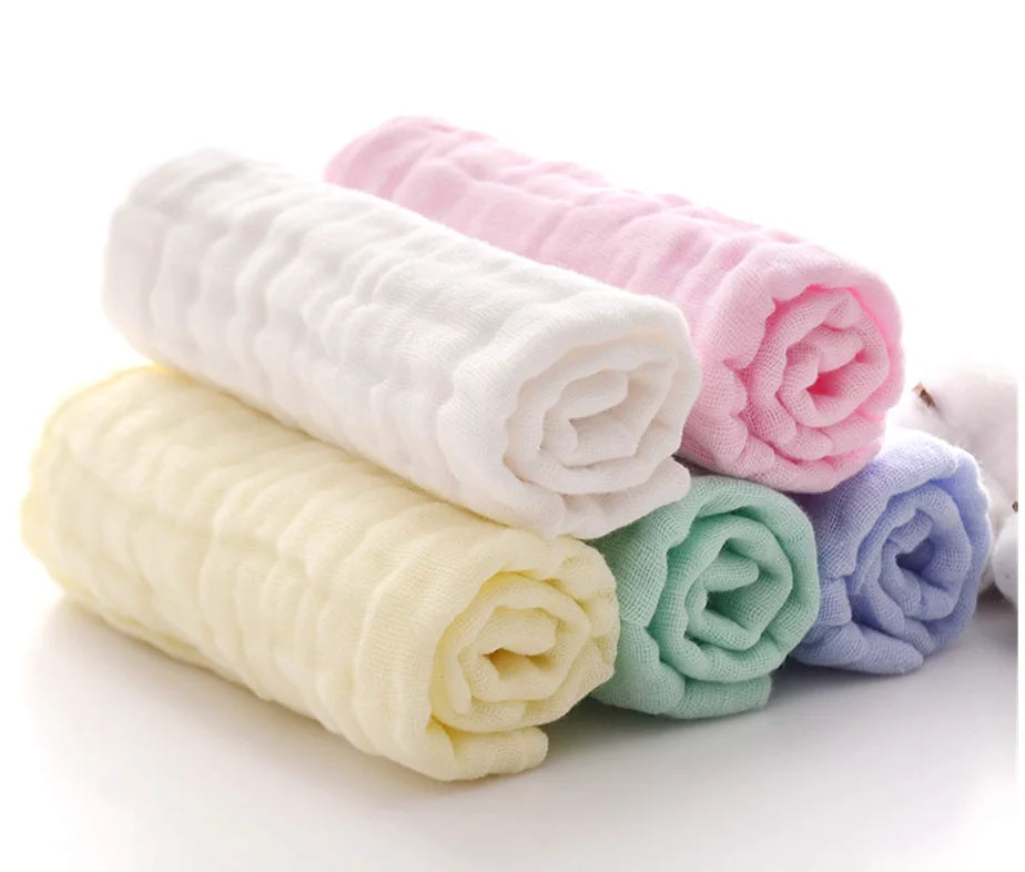 Stack of folded baby blankets in pastel colors on a white background