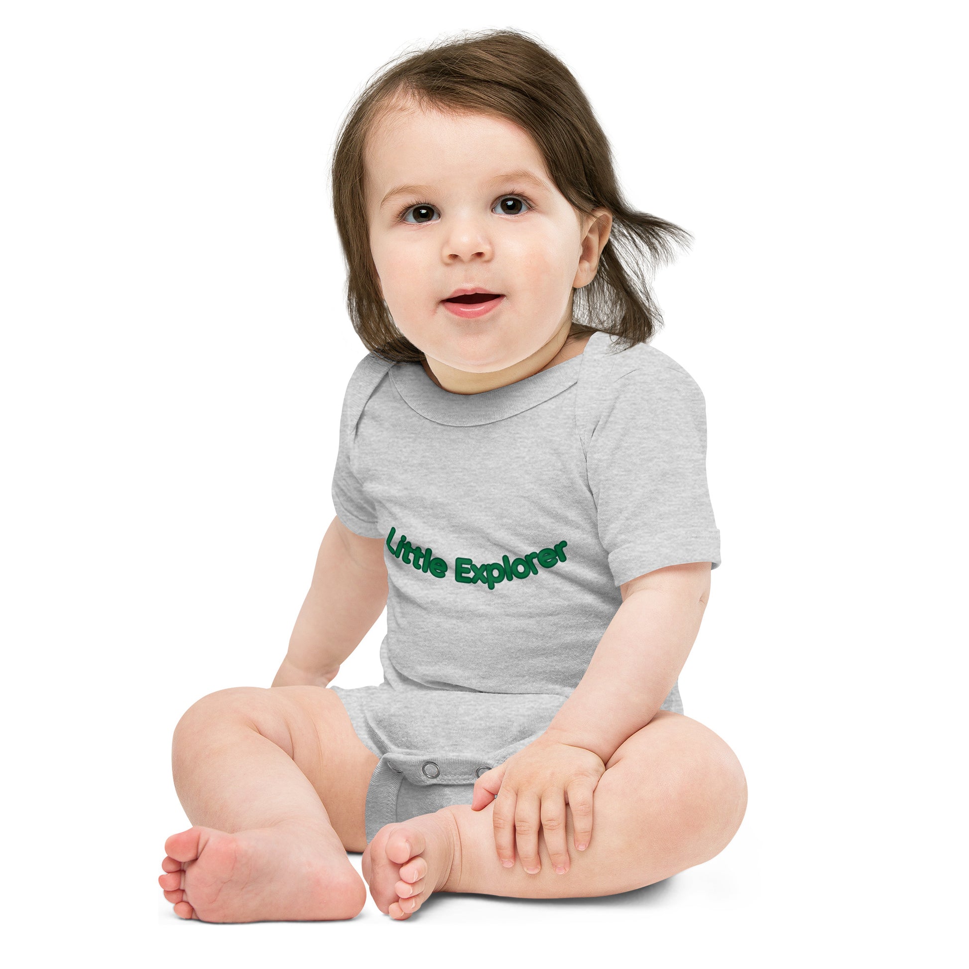 Child wearing a gray onesie with 'Little Explorer' text on a white background